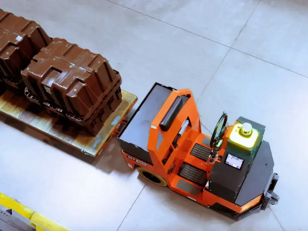 Autonomous tugger pulling palletized loads on a plant floor